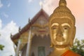 Close up face of buddha with temple as background