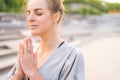 Close-up face of calm attractive young woman practicing yoga performing namaste pose with closed eyes outside in city Royalty Free Stock Photo