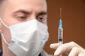 Close-up face of a caucasian doctor preparing a syringe for injection. Young male doctor in a protective mask and gloves Royalty Free Stock Photo