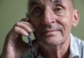 Close-up face of caucasian elderly man talking on smartphone. Pensioner with phone. Selective focus,