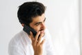 Close-up face of cheerful bearded young business man talking mobile phone, having conversation on smartphone, holding Royalty Free Stock Photo