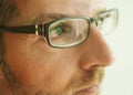 Close up face crop portrait of man in glasses looking thoughtful and serious in studio on a light background