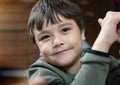 Close up face of cute little child boy looking at camera with smiling face, Candid shot mixed race kid sitting alone with happy