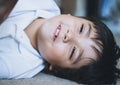 Close up face of cute little child boy lying on carpet, Candid shot mixed race kid playing alone with smiling face looking up,