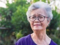 Close-up of face elderly woman smiling happiness, short white hair and looking at the camera, standing in garden. Asian senior Royalty Free Stock Photo