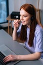 Close-up face of friendly young woman operator using headset and laptop computer during customer support via phone. Royalty Free Stock Photo