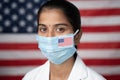 Close up face of Girl with I voted by main sticker on her medical mask with US flag as background - Concept of mail in voting in