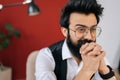 Close-up face of handsome Indian businessman wearing elegant formalwear sitting on chair and smiling looking away. Front Royalty Free Stock Photo