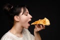 Close-up face of hungry young woman open mouth ready biting appetizing piece of pizza