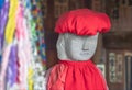 Close up on the face of a Jizo statue wearing a red knit cap and baby bib.
