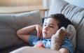 Close up face little boy sitting on sofa watching TV, Positive Kid lying on couch with dog toy in living room. Child relaxing at Royalty Free Stock Photo