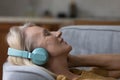Closeup older woman relax on sofa enjoy music through headphones