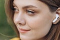 Close up face portrait of a lovely young fitness girl listening to music through wireless earphones outdoors Royalty Free Stock Photo