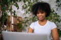 Close-up face of positive African-American businesswoman working on laptop computer sitting at desk at home office room Royalty Free Stock Photo