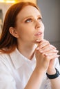 Close-up face of sad young woman praying holding folded hands in front of face at home, looking up. Royalty Free Stock Photo
