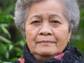 Close-up of face senior woman wearing a scarf, smiling and looking at the camera while standing in the garden Royalty Free Stock Photo