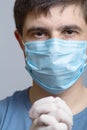Close up face of a serious young doctor in protective medical mask with surgical gloves on gray studio background, concept Royalty Free Stock Photo