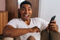 Close-up face of surprised African-American man receiving good news using mobile phone at home. Royalty Free Stock Photo