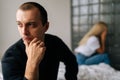 Close up face of thoughtful young man looking away not talking after dispute with sad wife sitting apart on bed Royalty Free Stock Photo