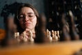 Close-up face of thoughtful young woman in elegant eyeglasses thinking about chess move sitting on floor in dark room Royalty Free Stock Photo