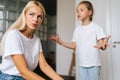 Close-up face of unhappy despair pensive young mother sitting on sofa listening mad little child daughter scolding