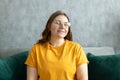 Close up face of young woman in glasses with beautiful smile siting on the sofa couch at home. 30s female rest and spend Royalty Free Stock Photo