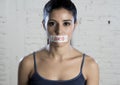 Close up face of young beautiful sad latin woman with mouth sealed on stick tape with the text no food