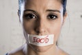 Close up face of young beautiful sad latin woman with mouth sealed on stick tape with the text no food Royalty Free Stock Photo