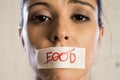 Close up face of young beautiful sad latin woman with mouth sealed on stick tape with the text no food Royalty Free Stock Photo