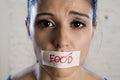 Close up face of young beautiful sad latin woman with mouth sealed on stick tape with the text no food Royalty Free Stock Photo