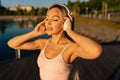 Close-up face of young pretty blonde woman in workout sportswear putting on wireless headphones to start running in city Royalty Free Stock Photo