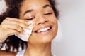 Close up of face of young happy attractive african washing off her makeup. Charming smiling mixed race girl wipes her face skin Royalty Free Stock Photo