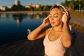 Close-up face of young pretty blonde woman in workout sportswear putting on wireless headphones to start running in city Royalty Free Stock Photo