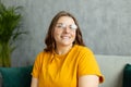 Close up face of young woman in glasses with beautiful smile siting on the sofa couch at home. 30s female rest and spend Royalty Free Stock Photo