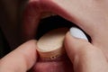 Close up of face of young woman taking drug. The drug addict is standing and putting a pill into her mouth. Royalty Free Stock Photo