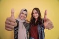 close up of faces of two smiling women looking at camera with thumbs up gesture