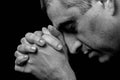 Close up of faithful mature man praying, hands folded in worship to god