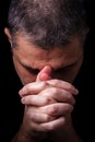 Close up of faithful mature man praying, hands folded in worship to god