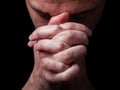 Close up of faithful mature man praying, hands folded in worship to god