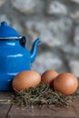 Close-up of farm eggs on hay, with zinc coffee maker on wooden table