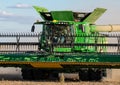 A close up of a farmer driving a John Deere combine harvester