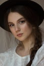 Close up fashion art photo of elegant beunette lady with natural makeup who wearing black hat and looking at the camera Royalty Free Stock Photo