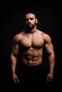 A portrait of a male with flexing muscles on a black background. Fitness training. A bodybuilder with a perfect body.