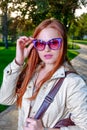 Close up fashion portrait of pretty seductive young woman with funny violet sunglasses, posing outdoor. Red lips, long Royalty Free Stock Photo