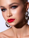 Close up fashion portrait of a very beautiful blond model with professional makeup, perfect skin and red lips.