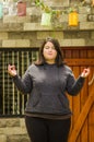 Close up of fat concentrating woman doing yoga exercise at outdoors, with both arms stretching, in a blurred background