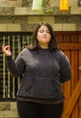 Close up of fat concentrating woman doing yoga exercise at outdoors, with one arm stretching, in a blurred background