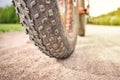 Close-up of fat mountain bike tire on dirty road. Fat bike wheel. Summer outdoor activity. Royalty Free Stock Photo