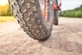 Close-up of fat mountain bike tire on dirty road. Fat bike wheel. Summer outdoor activity Royalty Free Stock Photo