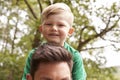 Close Up Of Father Carrying Son On Shoulders On Walk By River